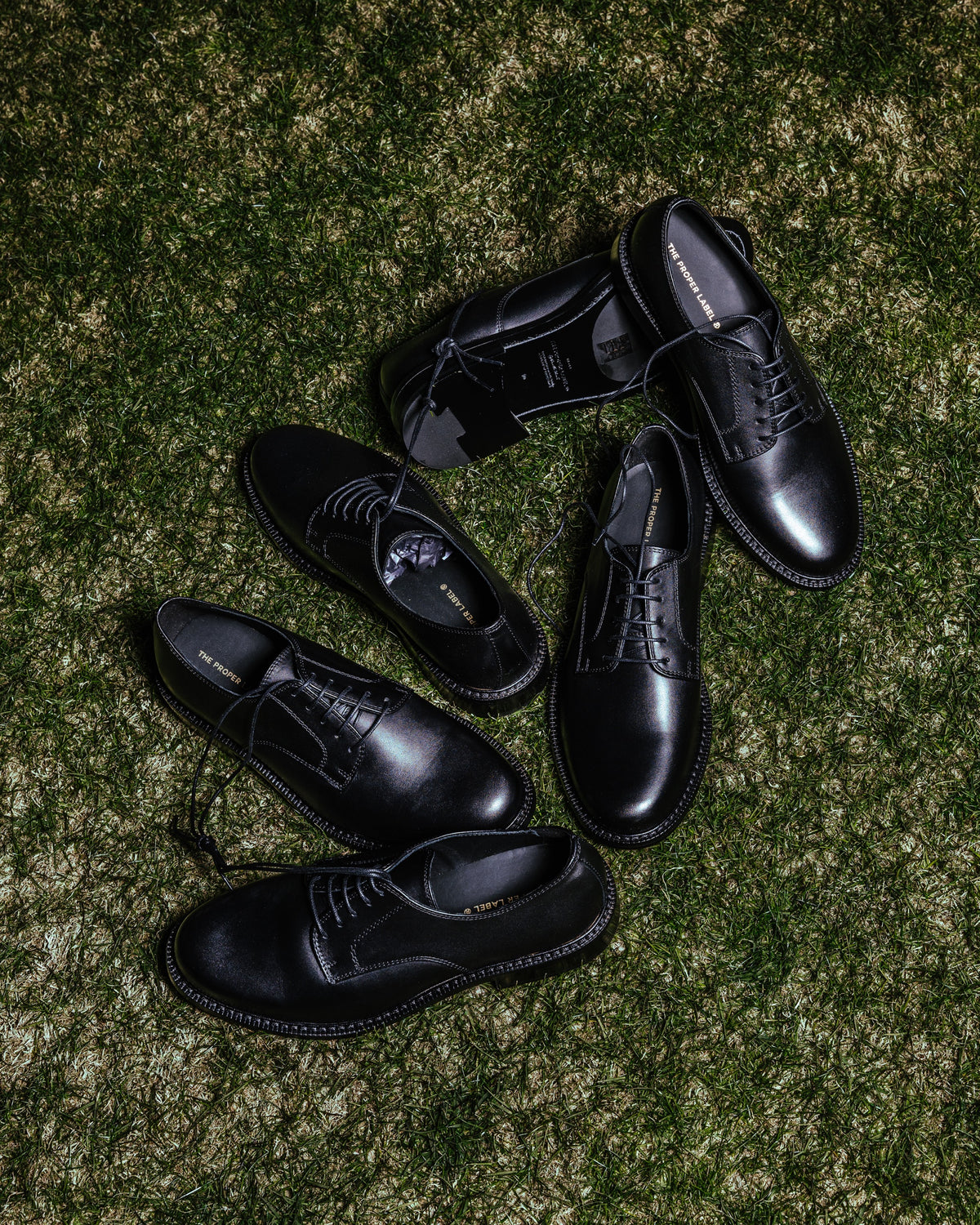 Souliers Legacy Derby noirs disposés sur le gazon.