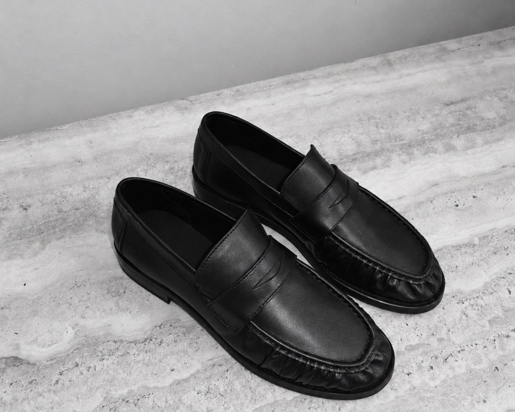 On stone, beside a bag, beneath a trouser: a shoe moving through ordinary settings.