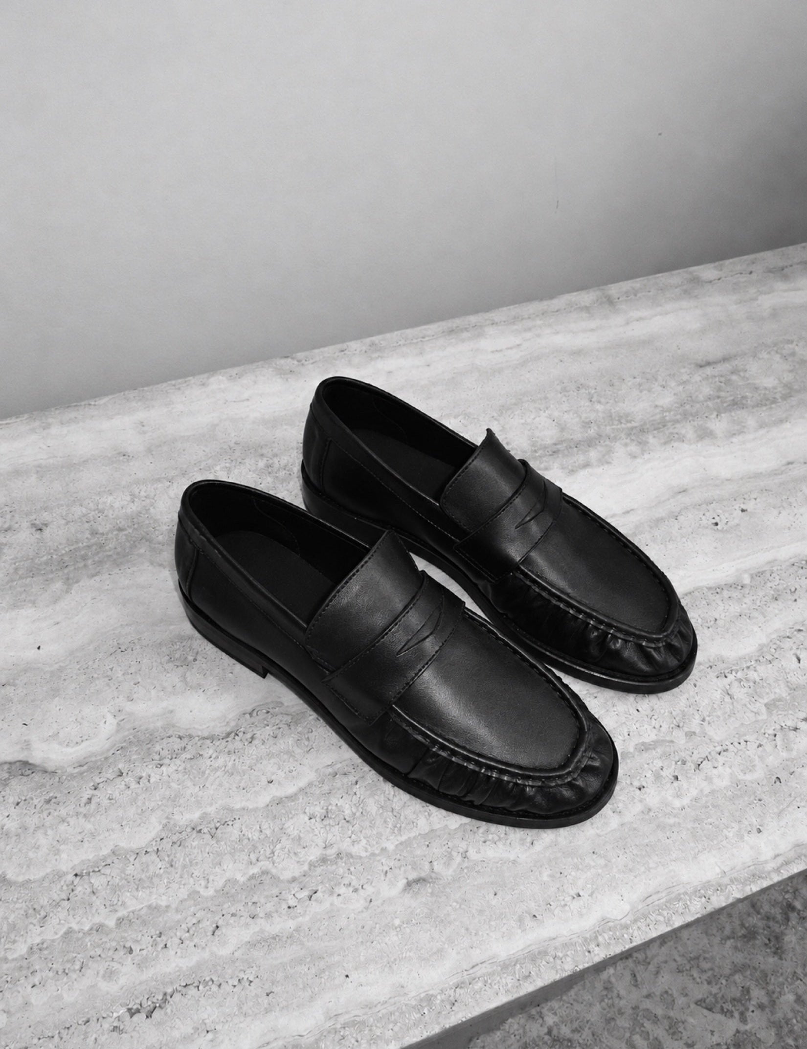 On stone, beside a bag, beneath a trouser: a shoe moving through ordinary settings.