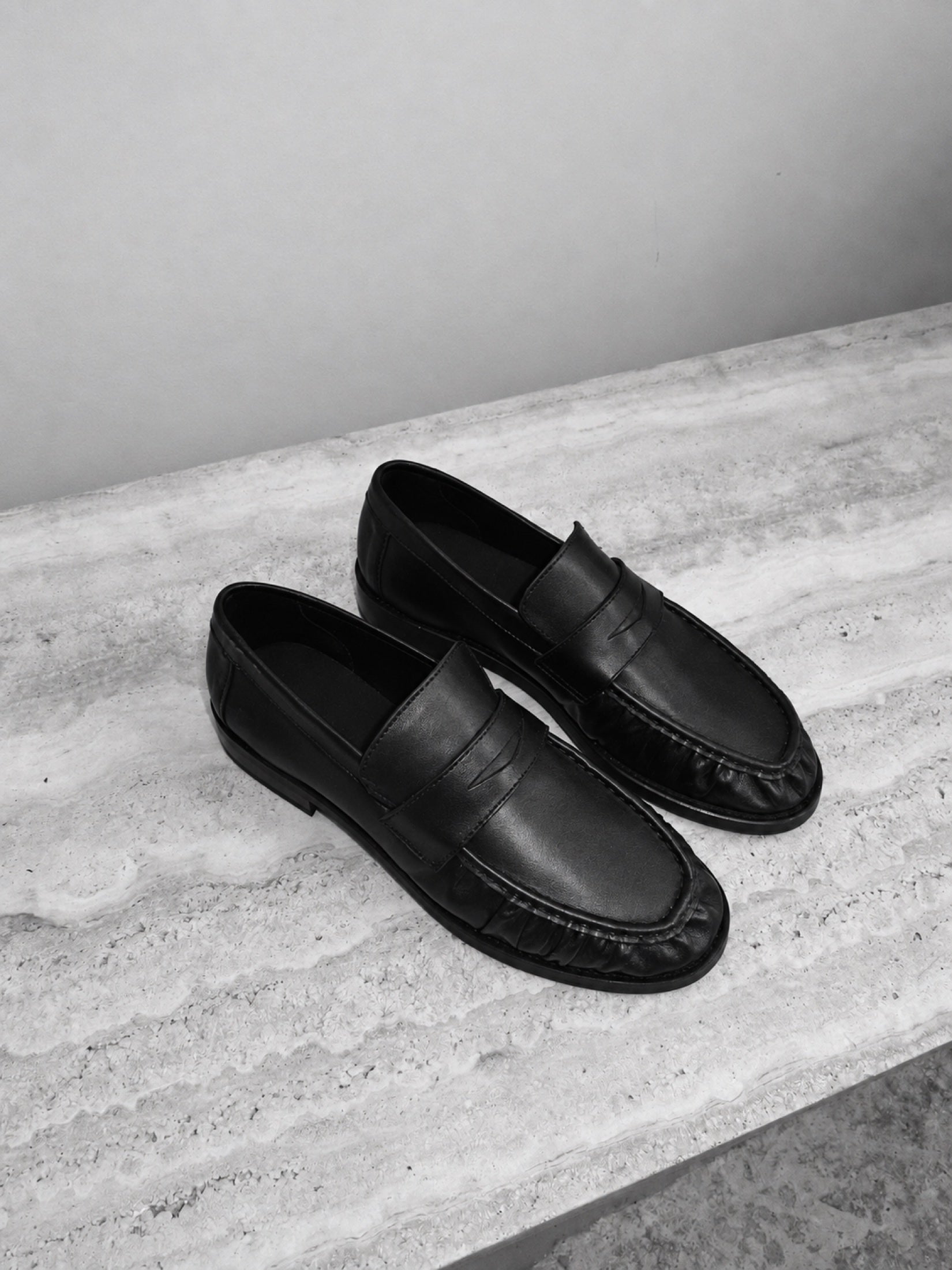 On stone, beside a bag, beneath a trouser: a shoe moving through ordinary settings.