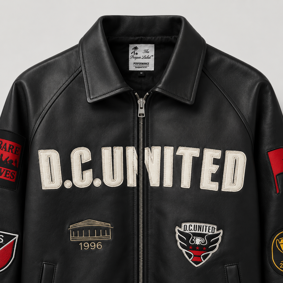 Close-up of the District Legacy Leather Jacket collar, leather texture and D.C. United chest lettering.
