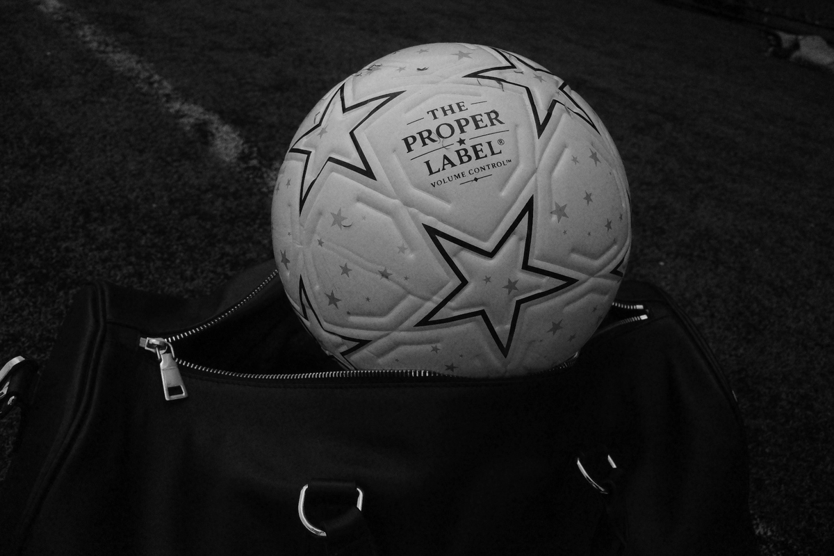 Close-up of The Proper Starball on a black travel bag, showing the stars, stitched panels and Proper Label signature.