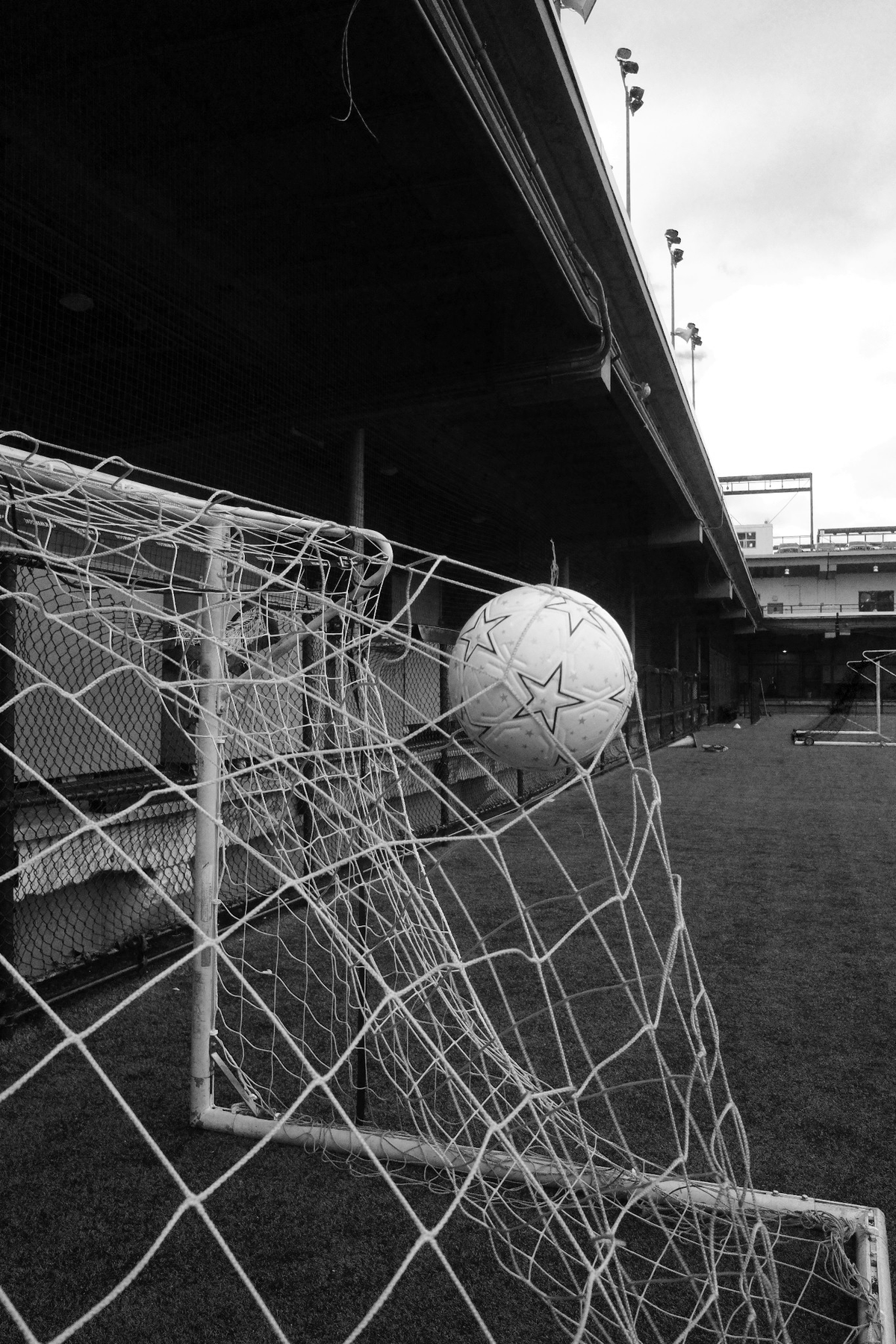 The Proper Starball caught in a football goal net, photographed in black and white.