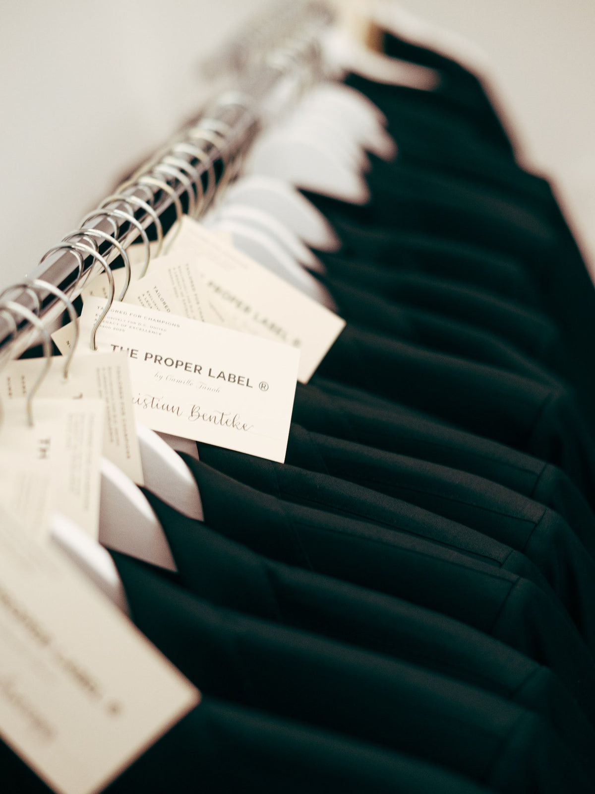 Jackets on a clothing rail with individual name tags, including Christian Benteke. Maison de Sport — Collection 005. Photography: Malike Sidibé, New York.