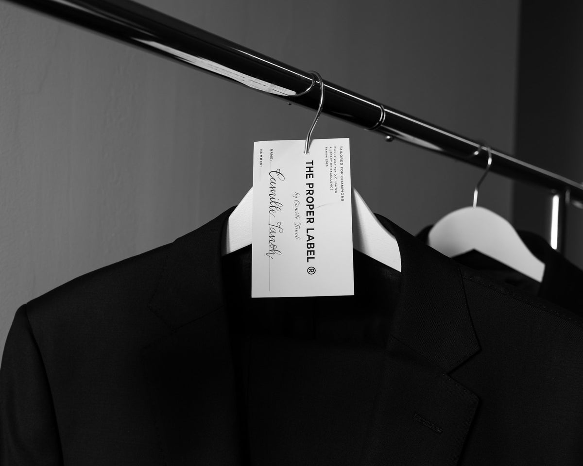 Black jacket, white hanger and named fitting tag on a clothing rail. Maison de Sport — Collection 005. Photography: Malike Sidibé, New York.