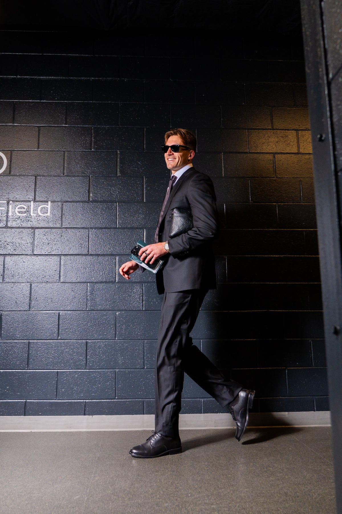 Lucas Bartlett wearing a dark suit, white shirt, tie and black lace-up shoes at Audi Field.