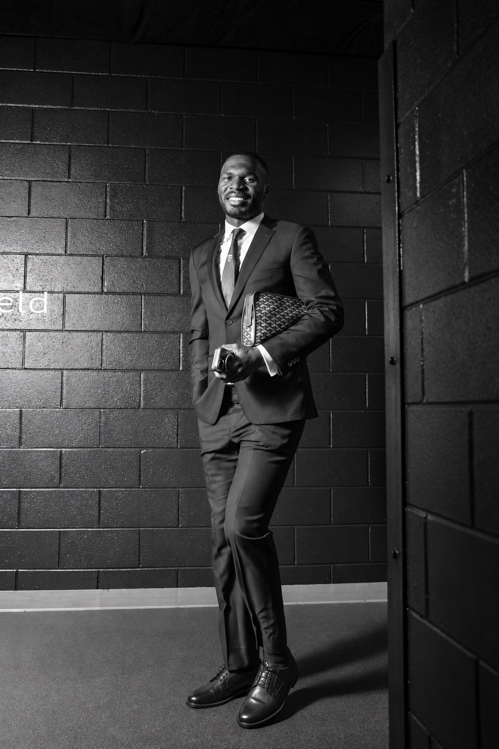 Christian Benteke wearing a dark suit, white shirt, club tie and black Derby shoes at Audi Field.