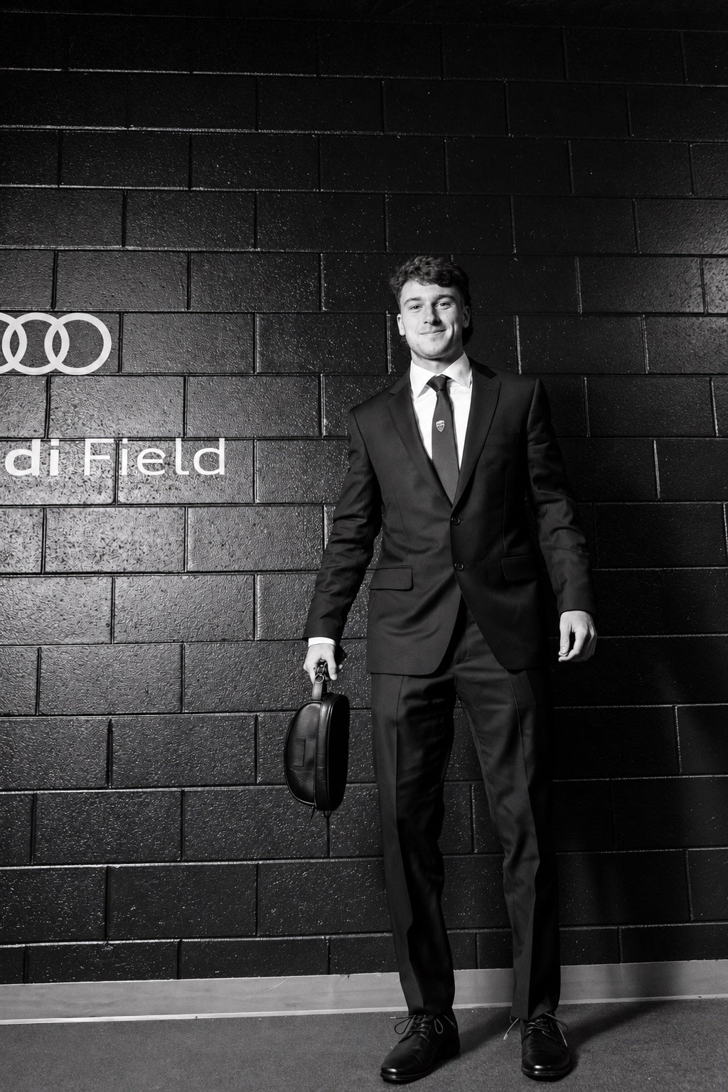 Jacob Murrell wearing a dark suit, white shirt, club tie and black Derby shoes at Audi Field.