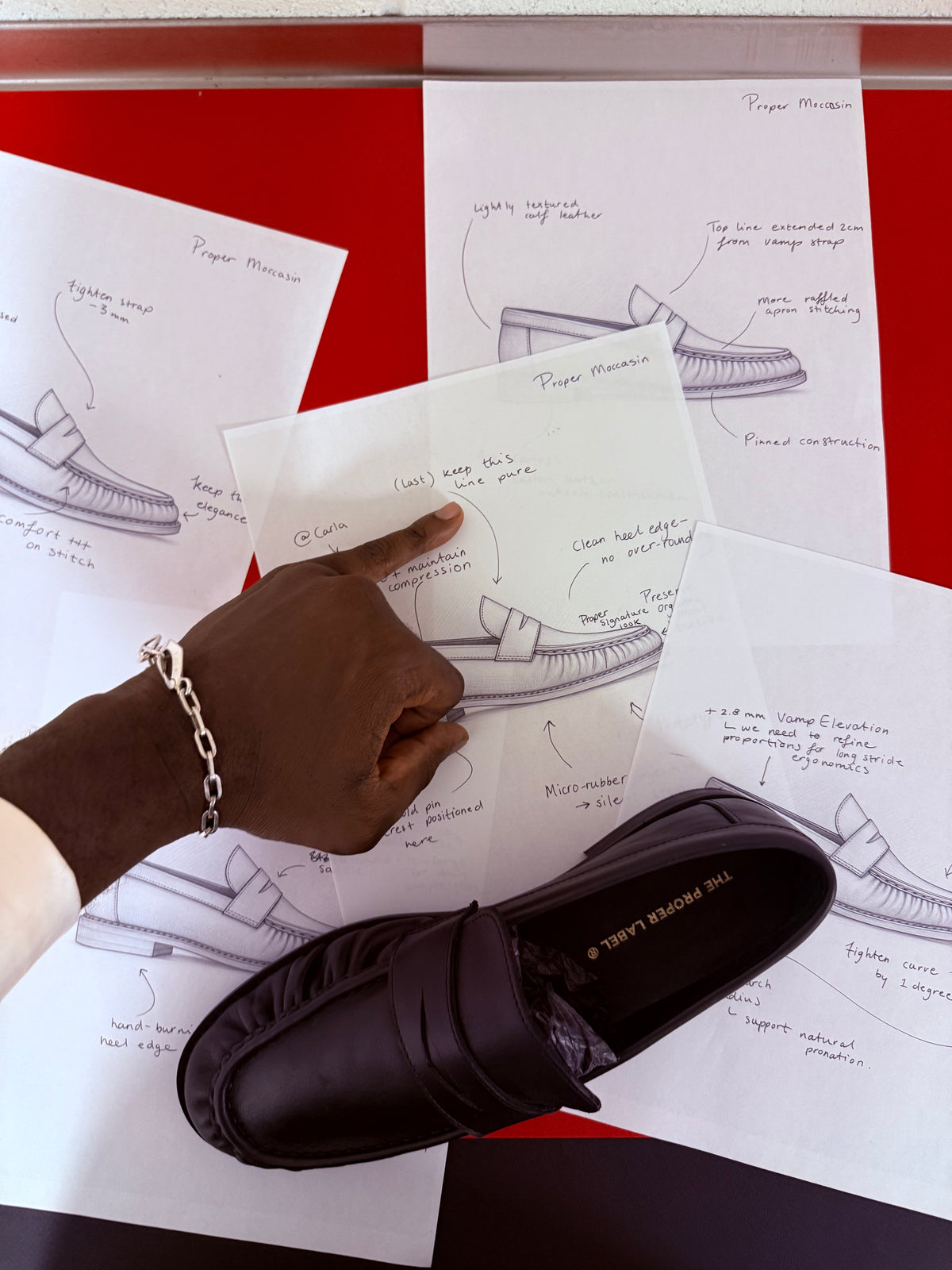Camille Tanoh reviews annotated Proper Moccasin drawings beside a black leather sample.