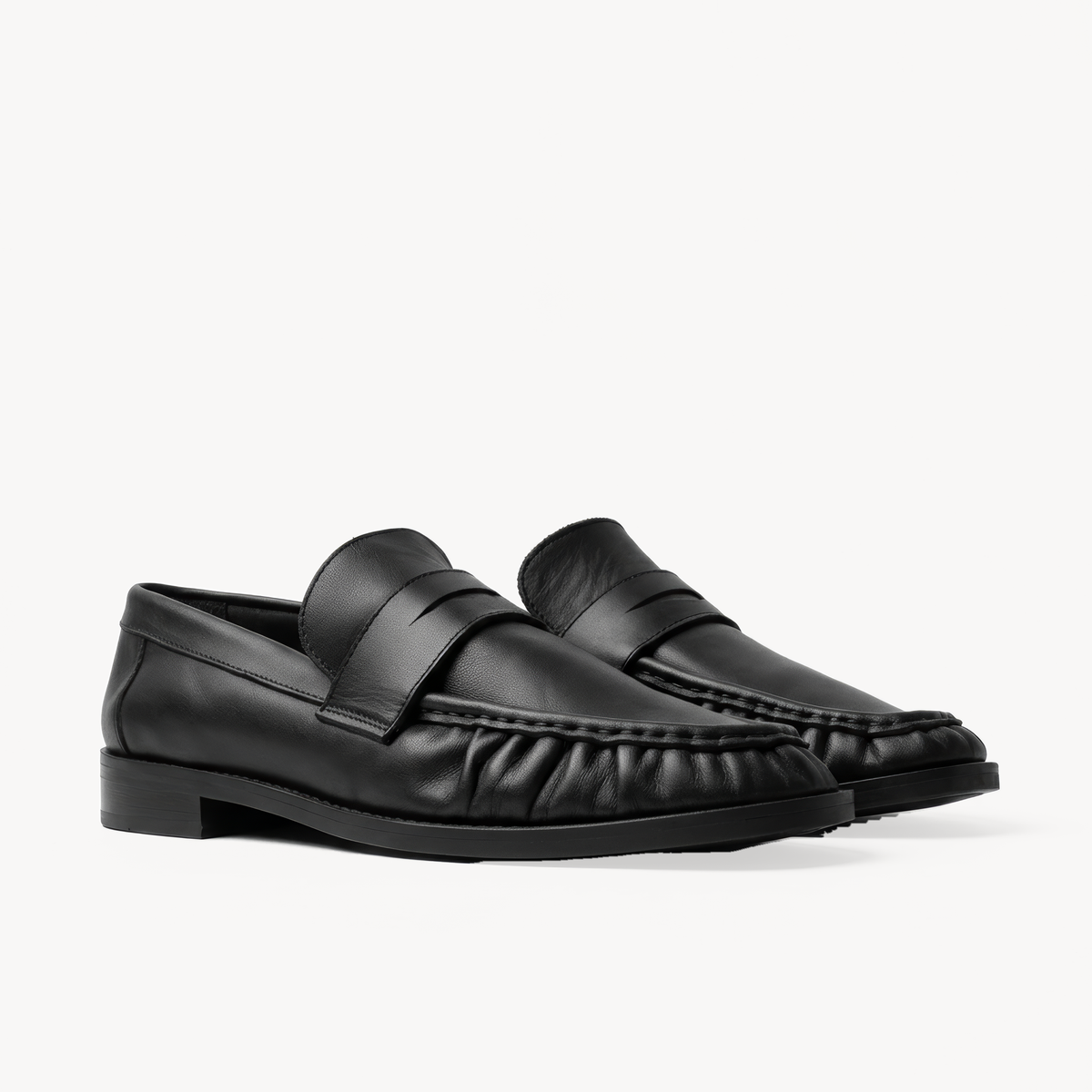 The Proper Moccasin, black leather loafers — pair in three-quarter view