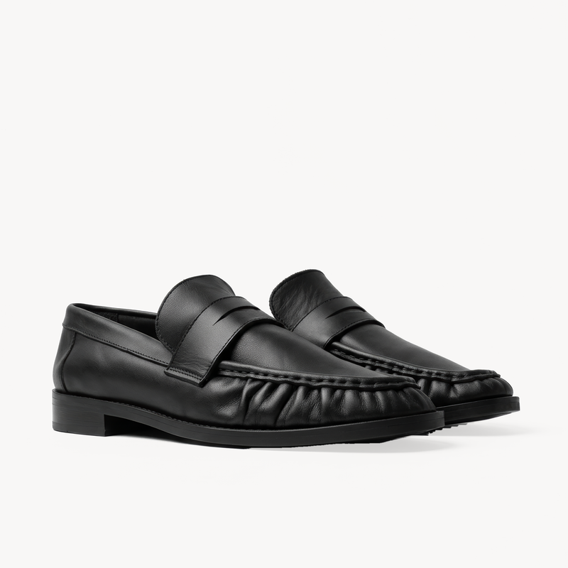 The Proper Moccasin, black leather loafers — pair in three-quarter view