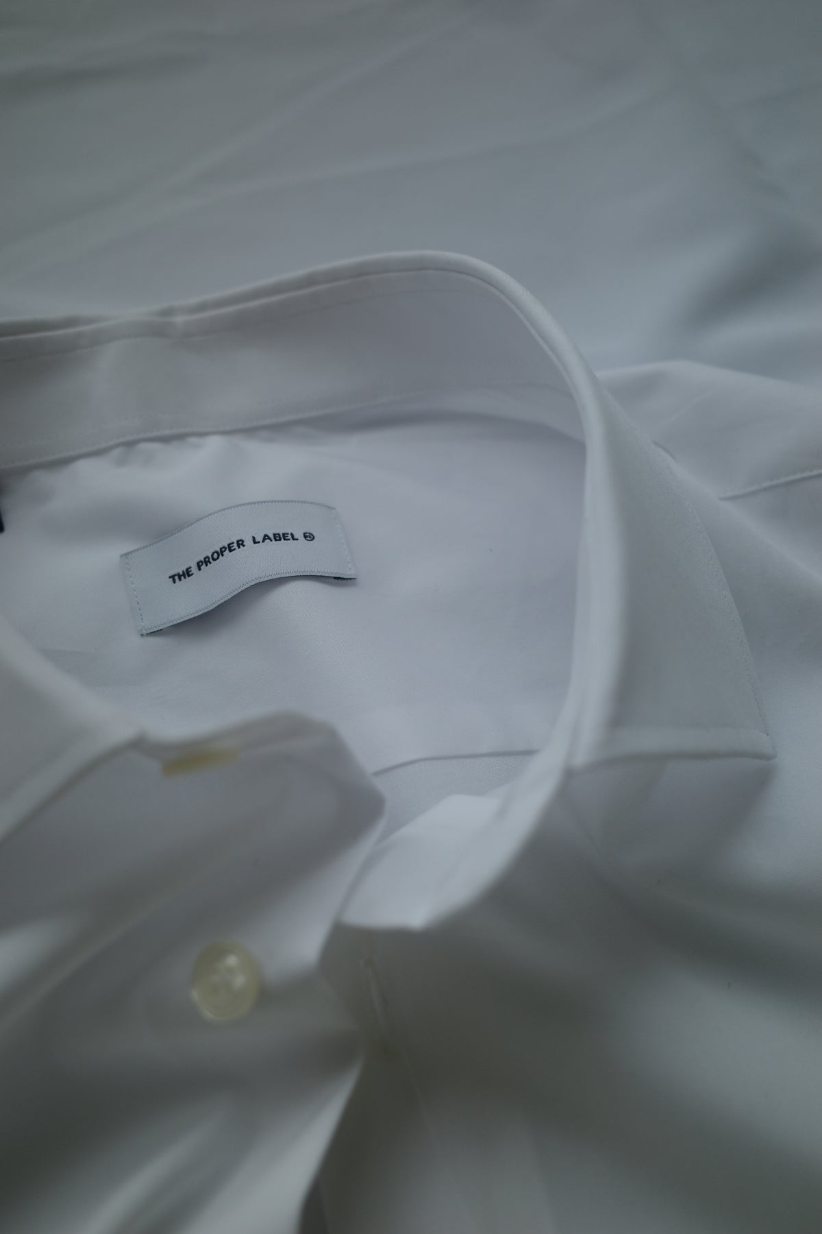 Close-up of a white shirt collar and its Proper Label signature.