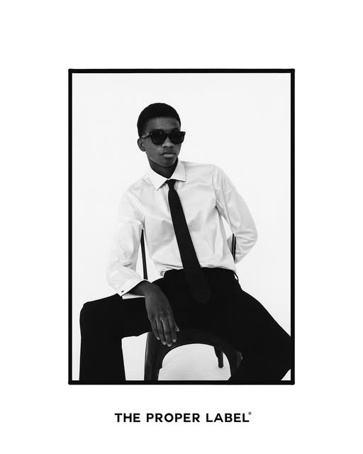 Black-and-white portrait of a seated man in a white shirt and tie.