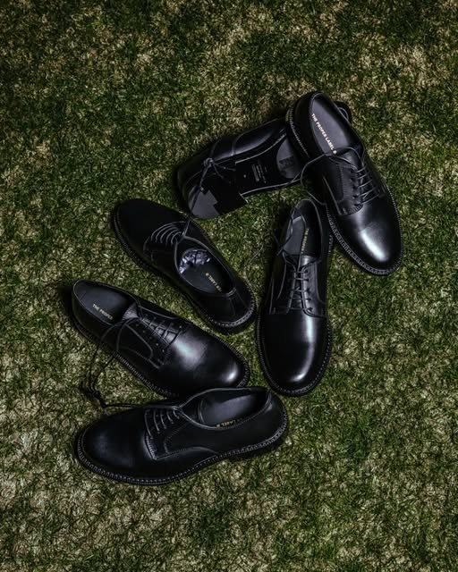 Black Derby shoes on artificial grass.