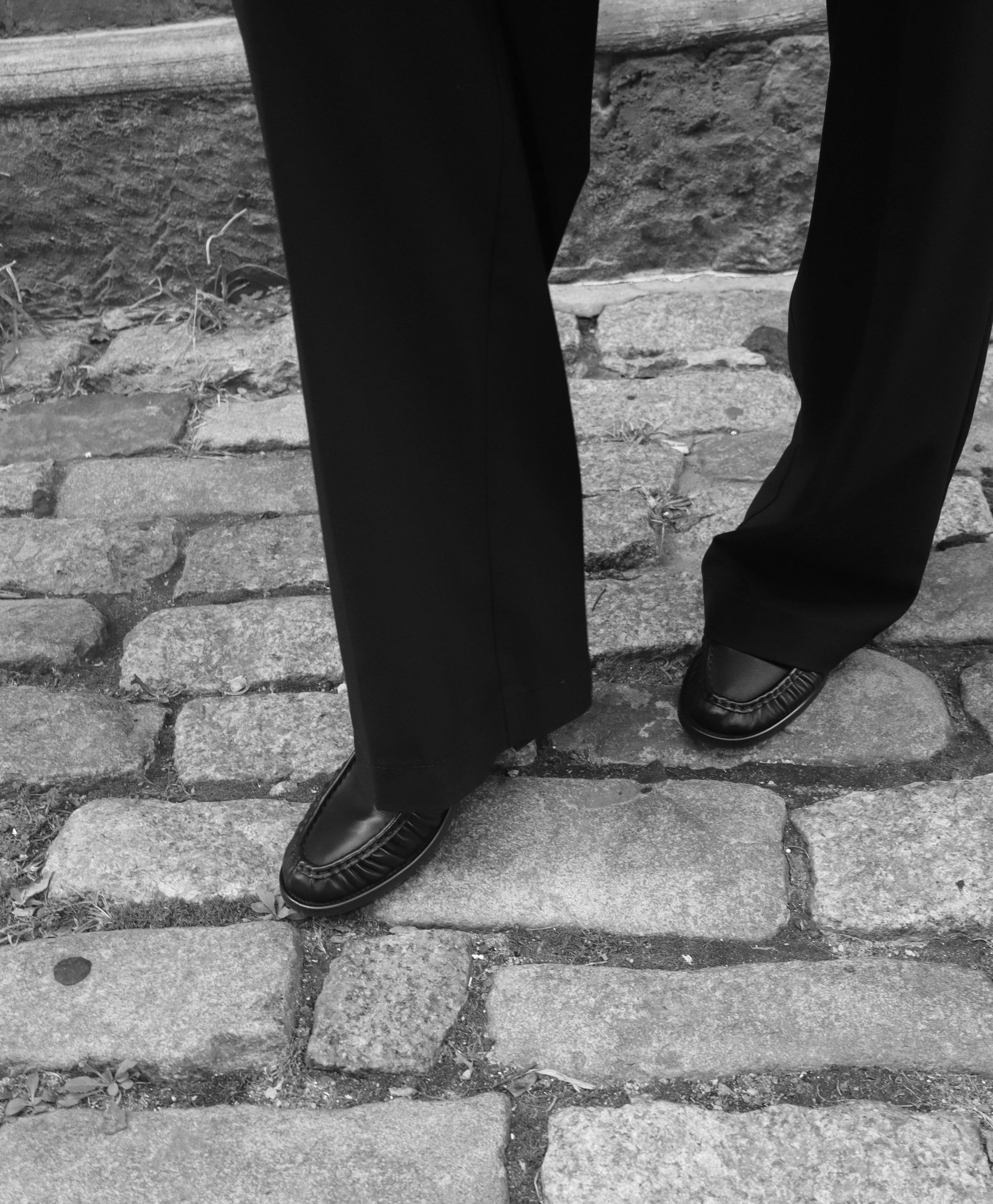 Julia's black loafers and tailored trousers on New York cobblestones.