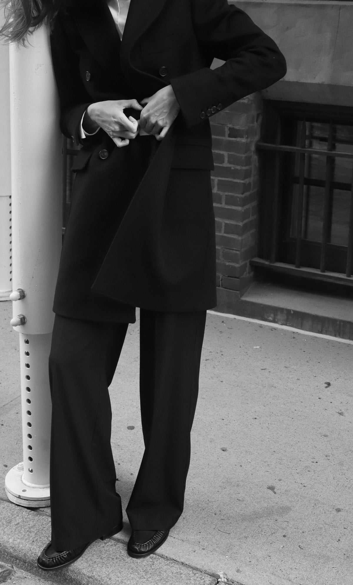 Julia fastening her double-breasted coat, cropped below the face.