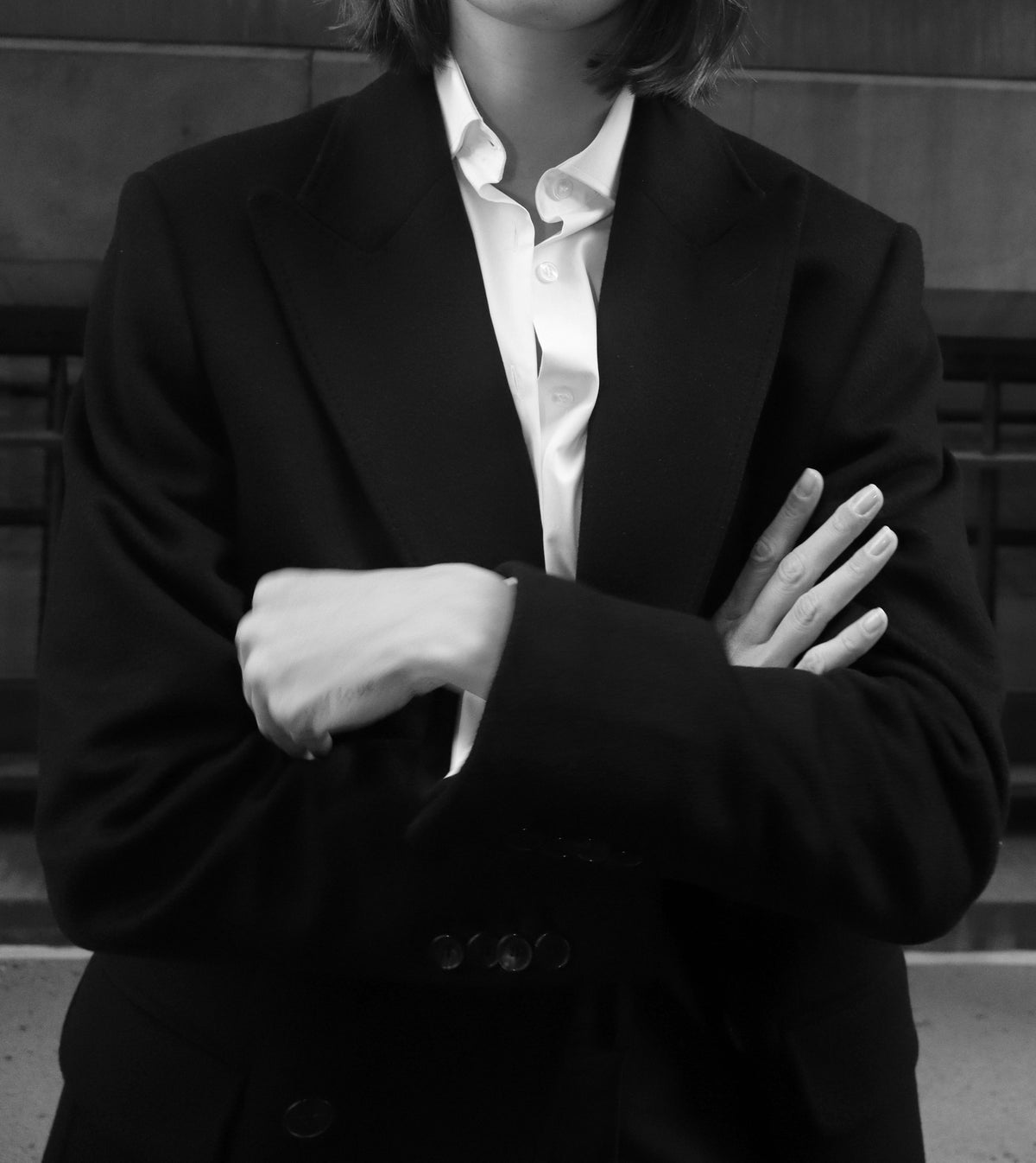 Julia in dark tailoring and a white shirt, arms crossed; cropped below the lips.