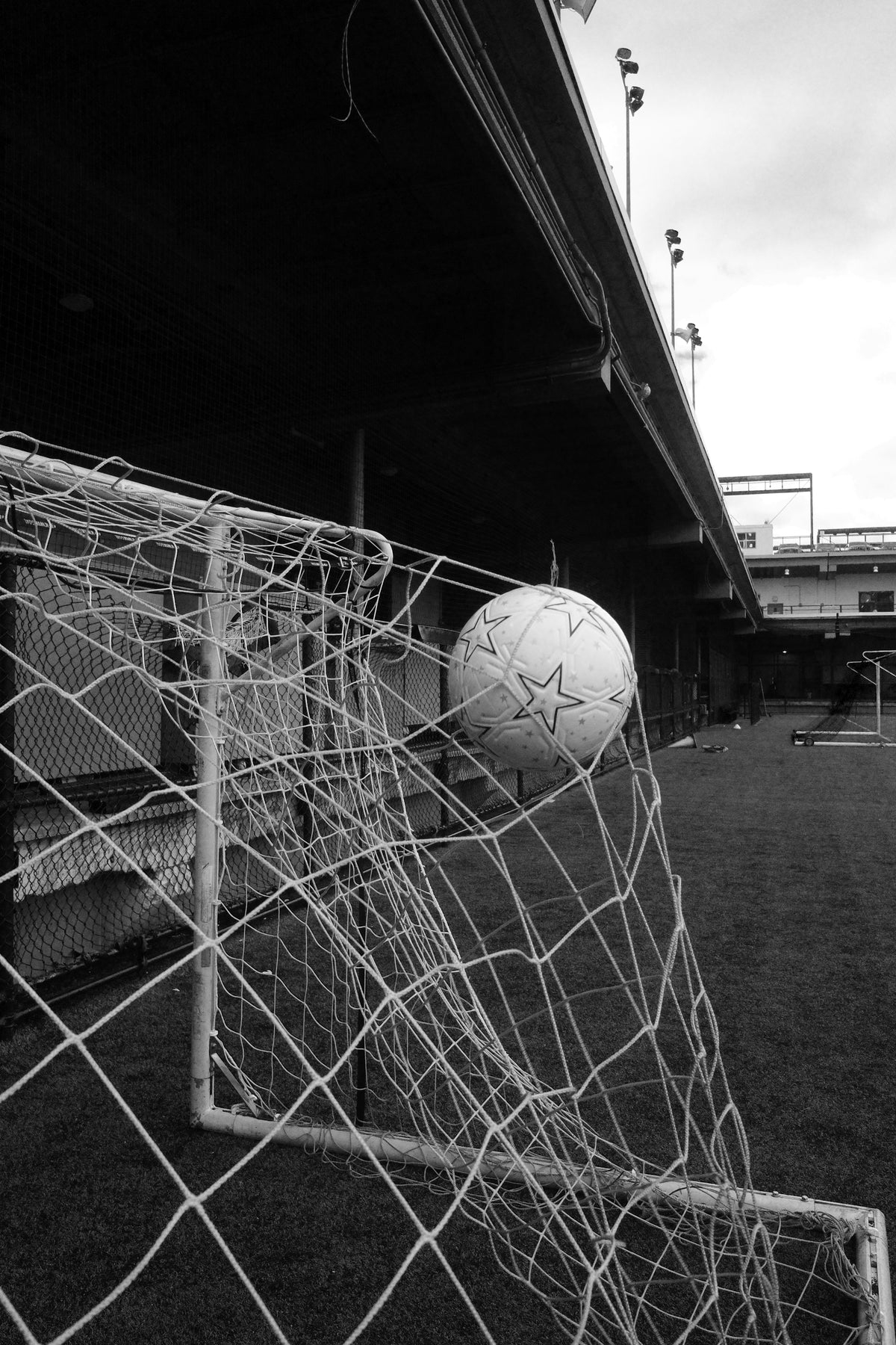 The Proper Label football caught in a goal net on an urban pitch