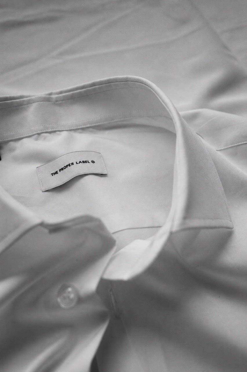 Black-and-white close-up of The Proper Poplin Shirt collar, stitching and The Proper Label signature.