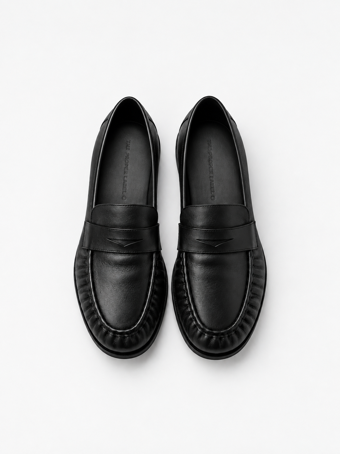 Campaign study of black Proper Mocassin loafers worn with charcoal tailored trousers.