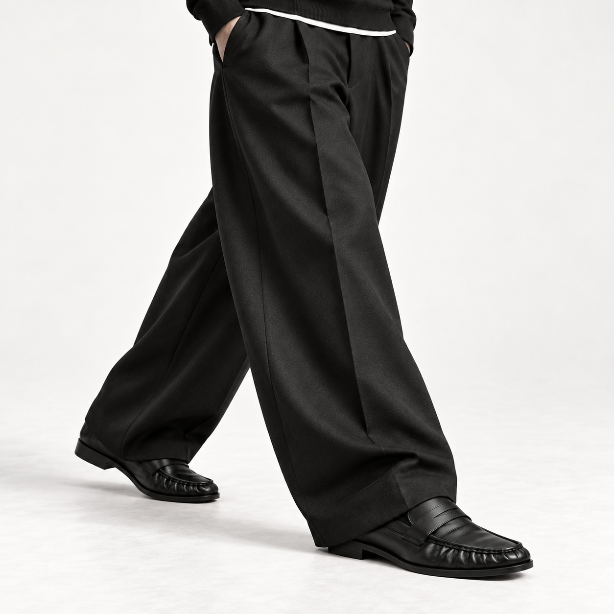 The Proper Moccasin® — Obsidian Black, an open stride beneath wide black trousers.