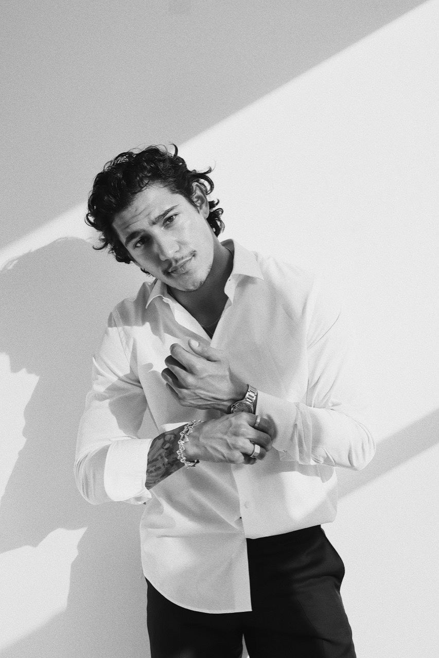 Gabriel Robles adjusting a white shirt cuff in sunlight.