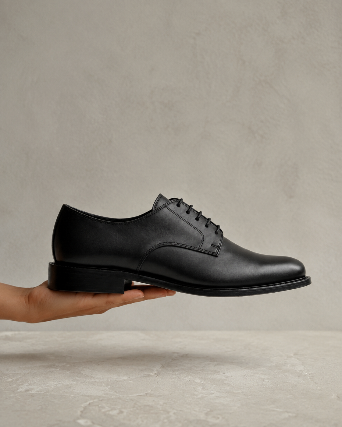 The Legacy Derby in profile, supported by a hand above pale limestone