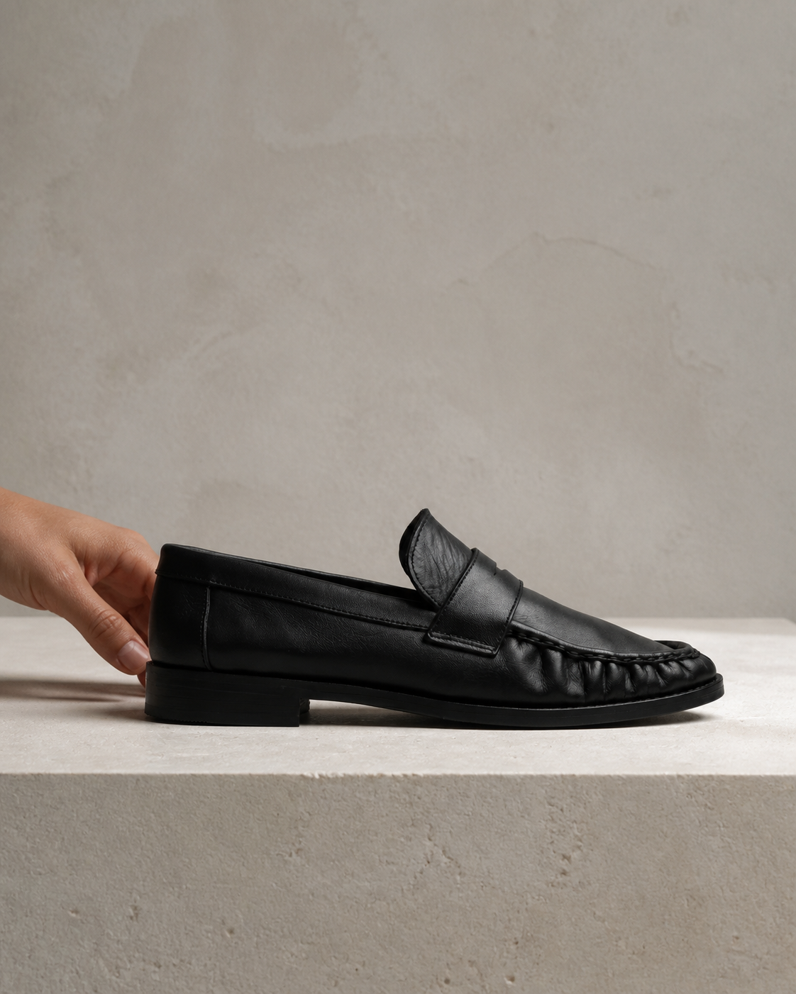 The Proper Moccasin® in profile on limestone, with a hand at the heel