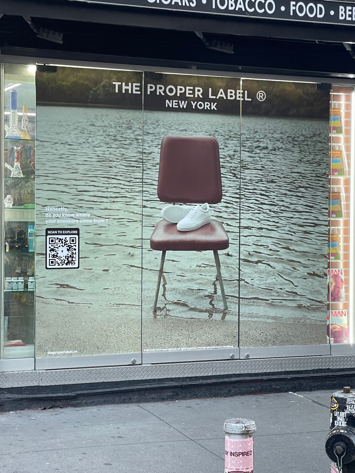 A shop window displays The Proper Label campaign with white sneakers on a chair in water.