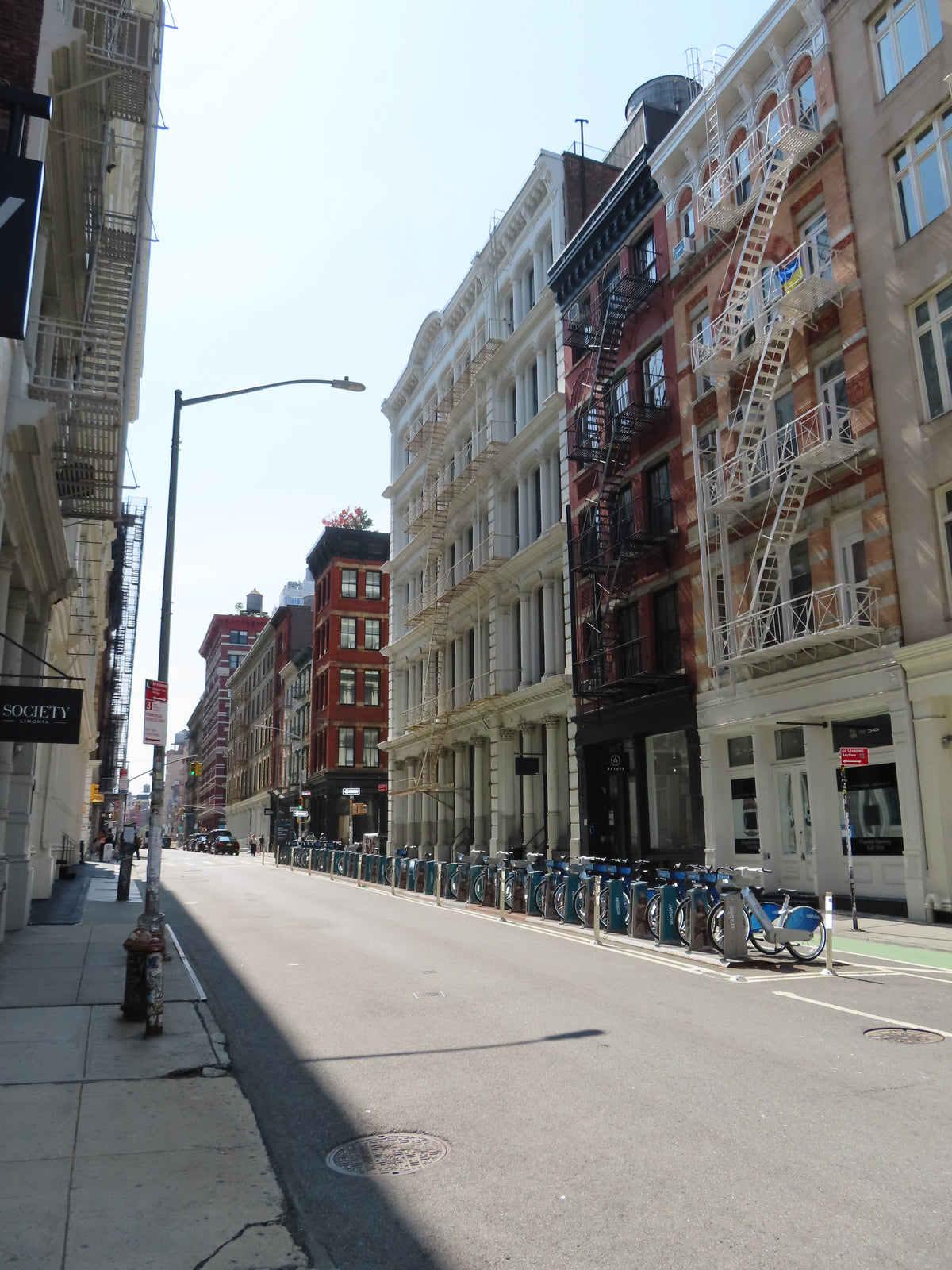 Cast-iron facades and fire escapes on a sunlit SoHo street in New York