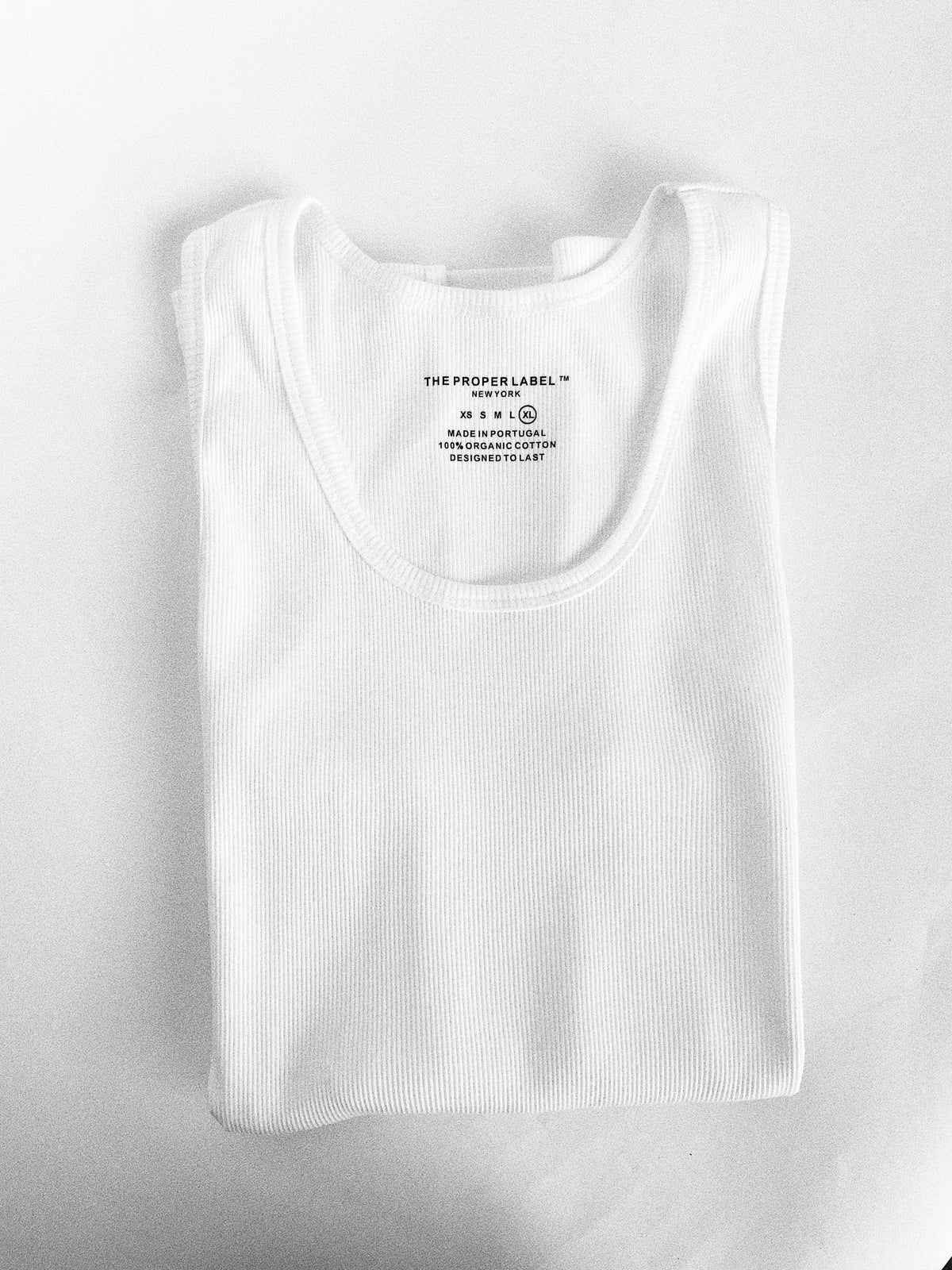 Folded white ribbed cotton tank with its printed composition and origin label.