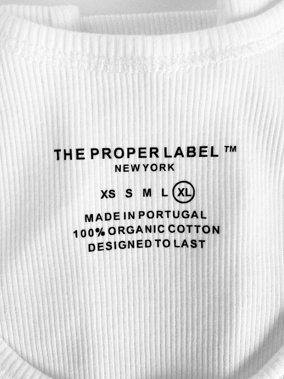 Printed garment label reading Made in Portugal, 100% organic cotton, Designed to last.