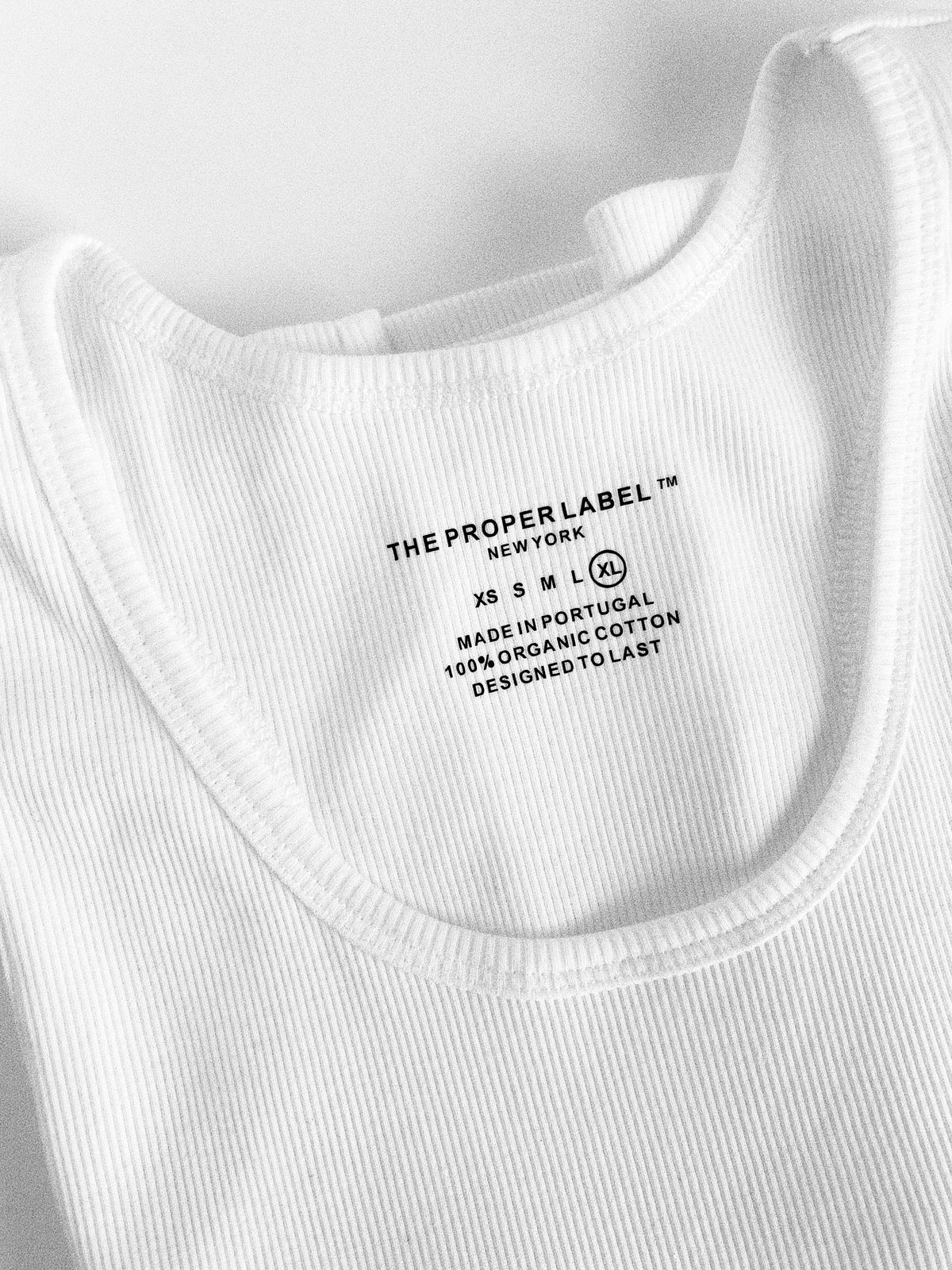 Close view of the ribbed white cotton neckline and its stitching.