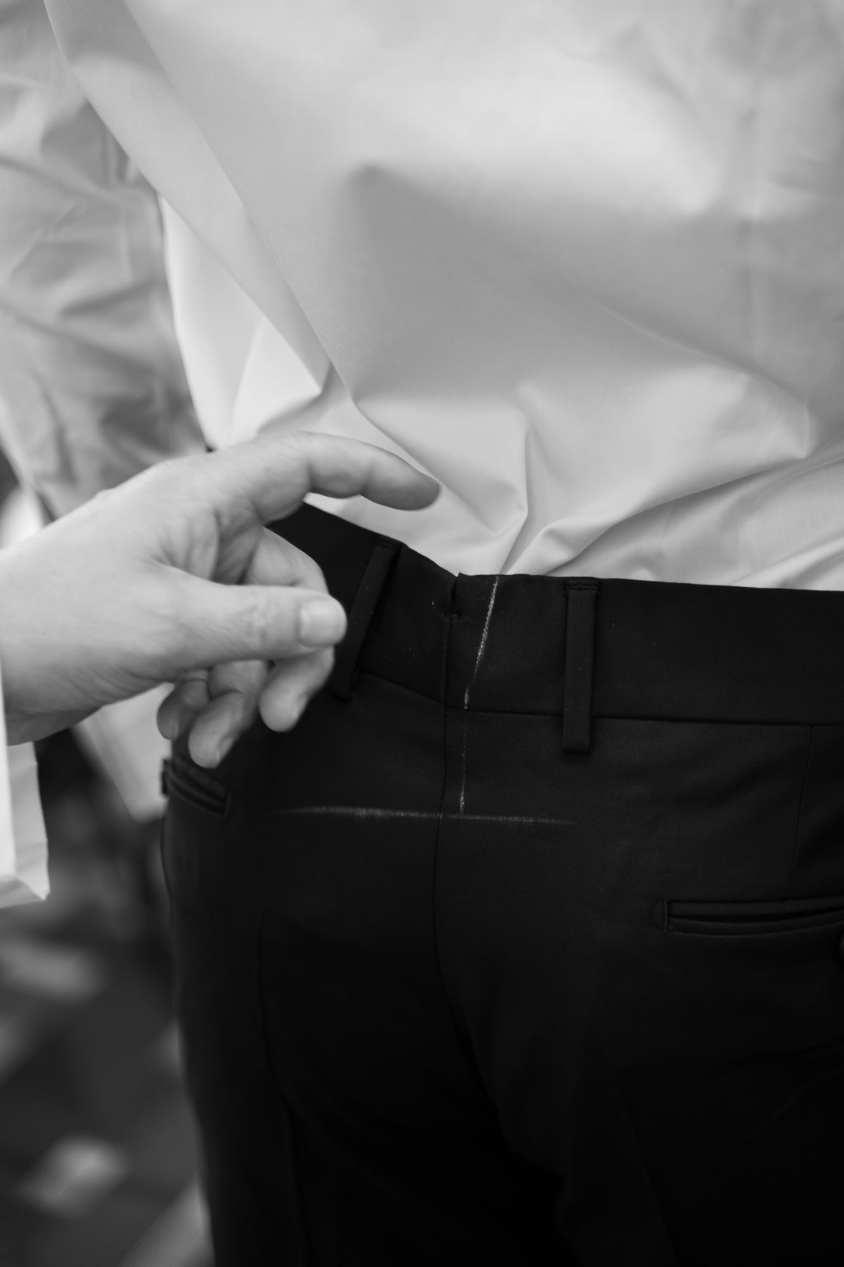 Marques à la craie et vérification à la main de la coupe d’un pantalon.