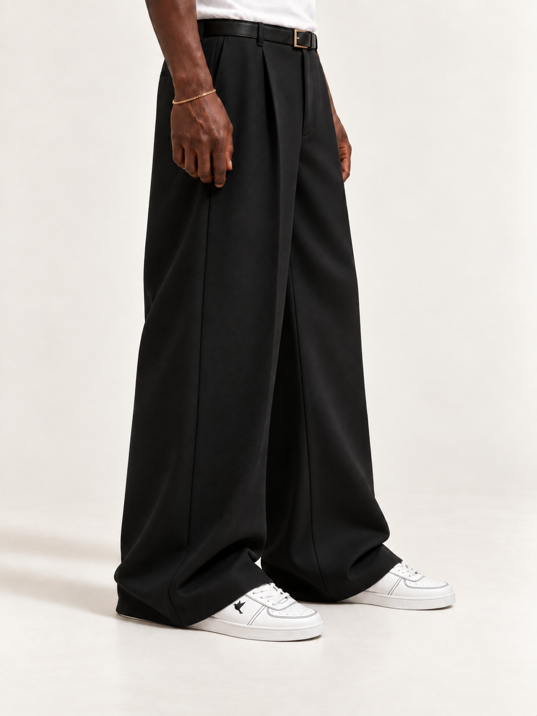 The Proper Fly Sneaker — White / Black, worn with long black trousers, a tucked white T-shirt, a slim belt and discreet gold-tone accessories.