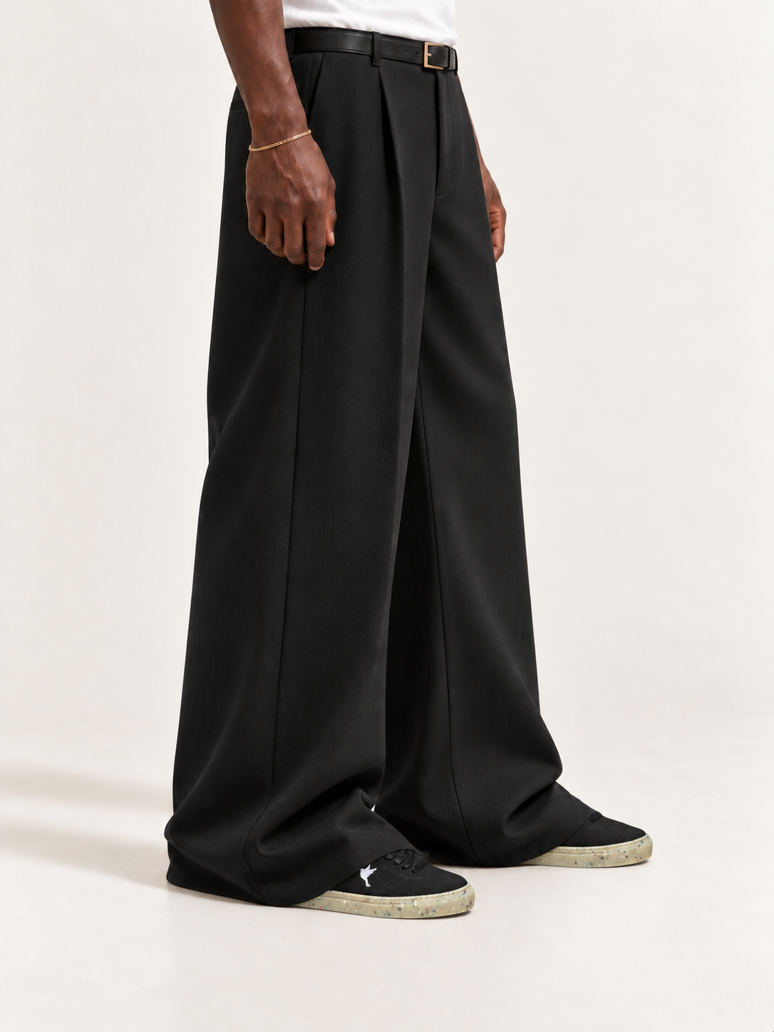 The Hampton Sneaker — Black, worn with long black trousers, a tucked white T-shirt, a slim belt and discreet gold-tone accessories.