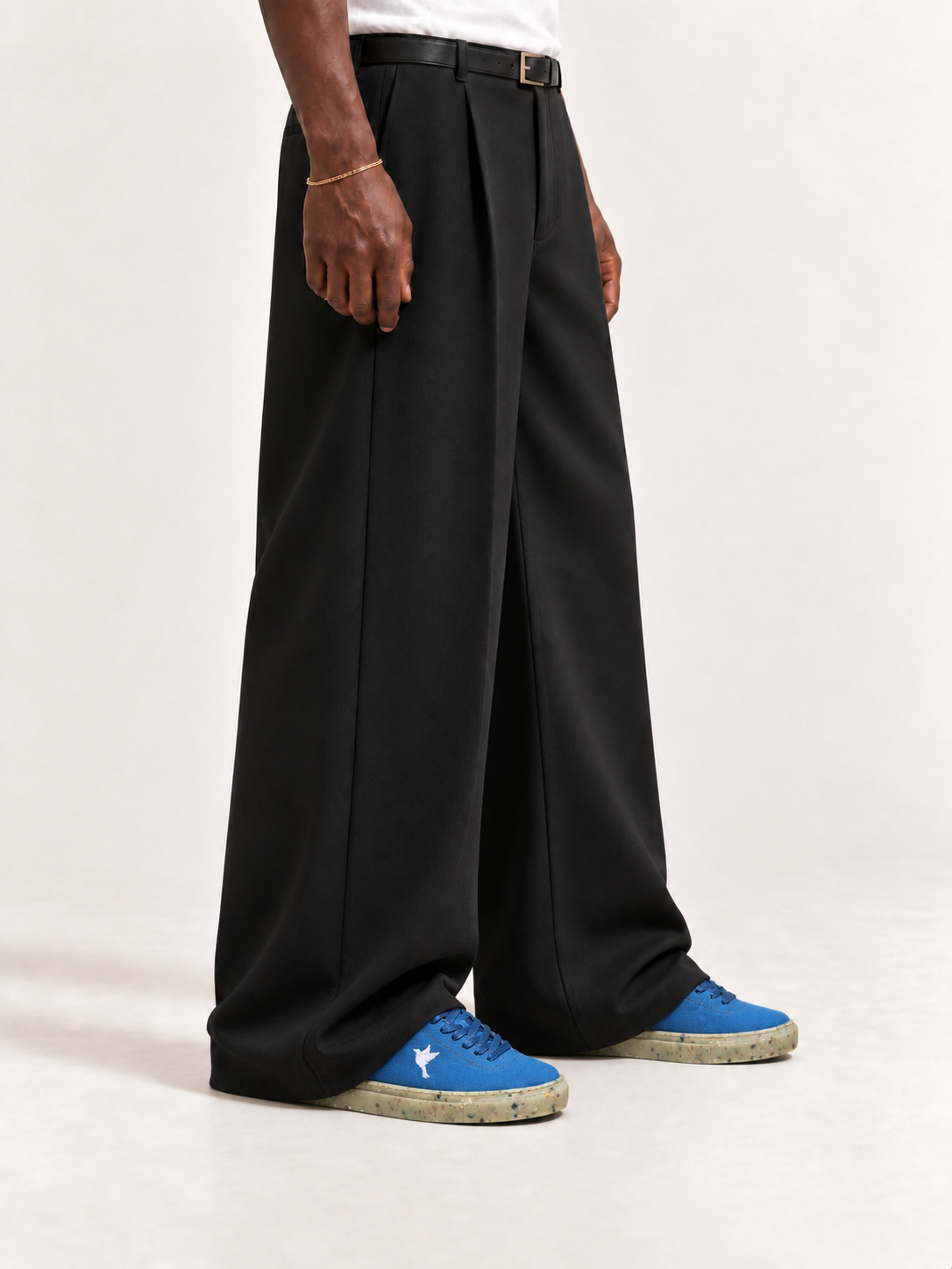 The Hampton Sneaker — Blue, worn with long black trousers, a tucked white T-shirt, a slim belt and discreet gold-tone accessories.