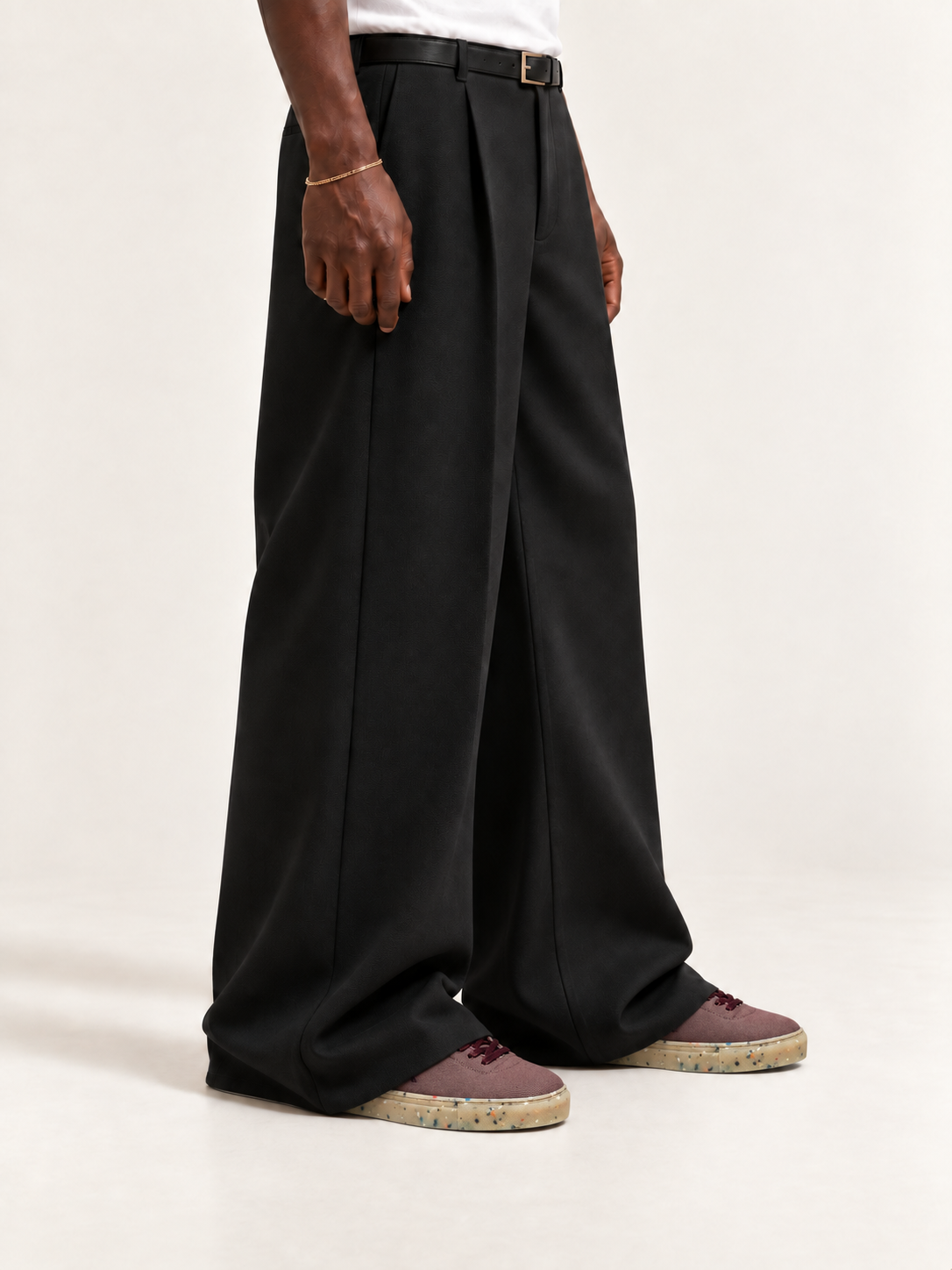 The Hampton Sneaker — Bordeaux, worn with long black trousers, a tucked white T-shirt, a slim belt and discreet gold-tone accessories.