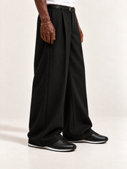 The Proper Runner — Black, worn with long black trousers, a tucked white T-shirt, a slim belt and discreet gold-tone accessories.