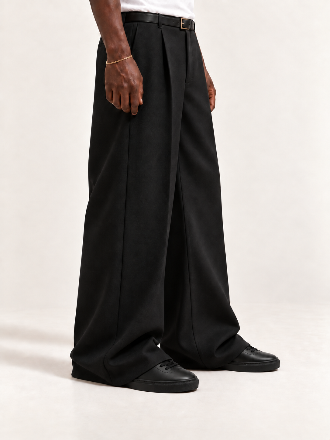 The Proper Sneaker — Black, worn with long black trousers, a tucked white T-shirt, a slim belt and discreet gold-tone accessories.