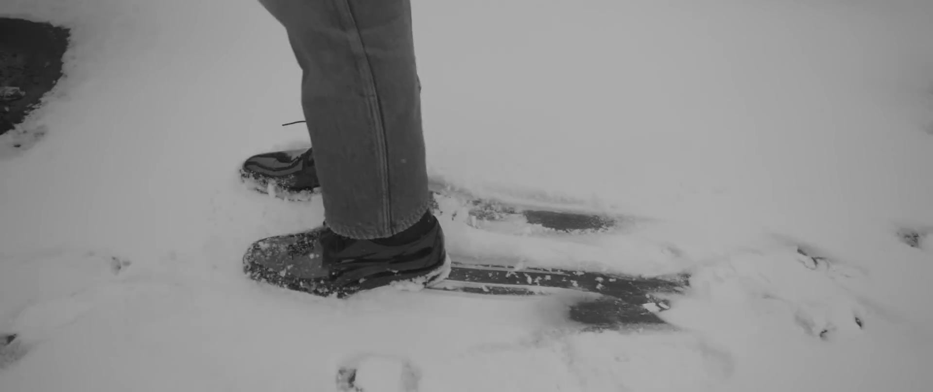 Des chaussures noires à lacets et des bas de pantalon dans la neige.