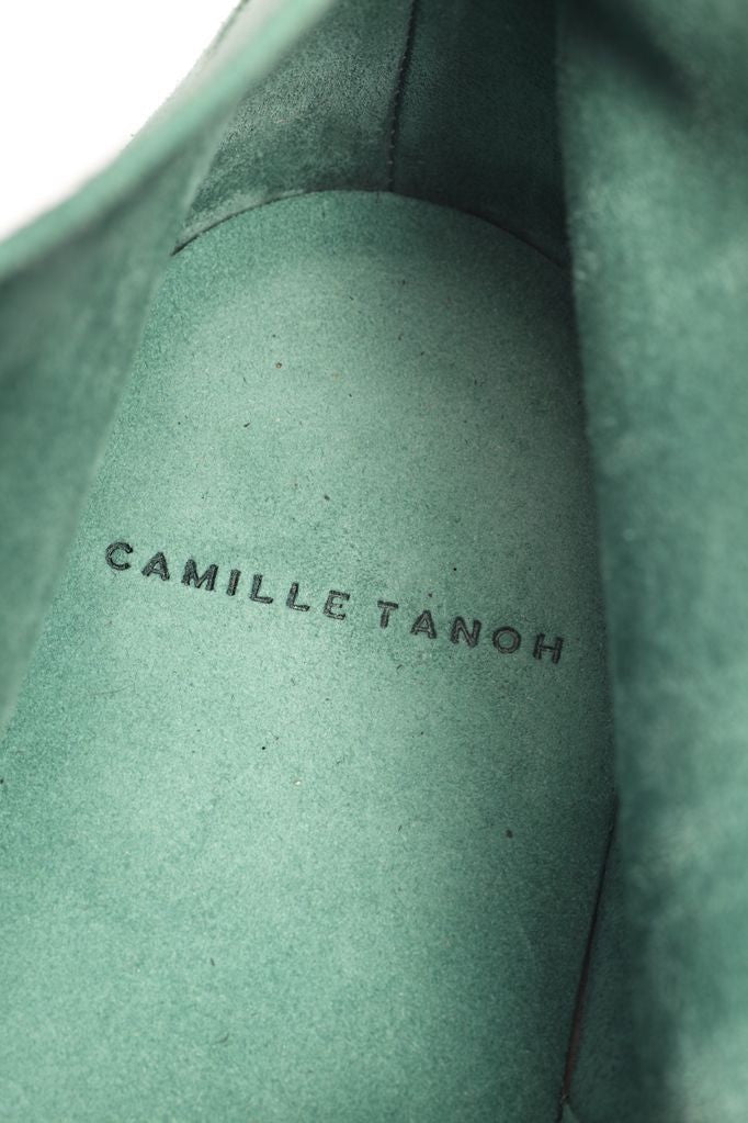 Gros plan de l’intérieur vert d’une chaussure, marqué CAMILLE TANOH