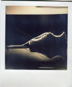 Polaroid of a sneaker and its reflection against a dark background.
