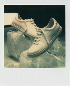Polaroid of two white sneakers arranged on translucent blocks.